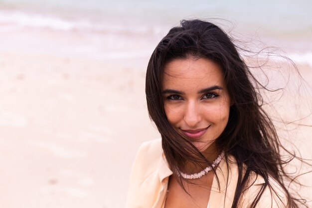 Retrato romántico de mujer en la playa en día ventoso, luz cálida del atardecer.