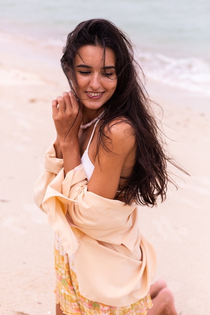 Retrato romántico de mujer en la playa en día ventoso, luz cálida del atardecer.