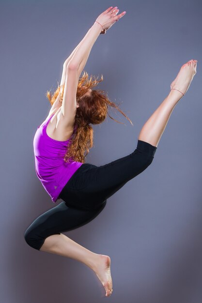 Retrato de ropa deportiva hermosa joven trabajando en fondo gris. Colocar chica deportiva haciendo yoga avanzado, pilates, fitness.