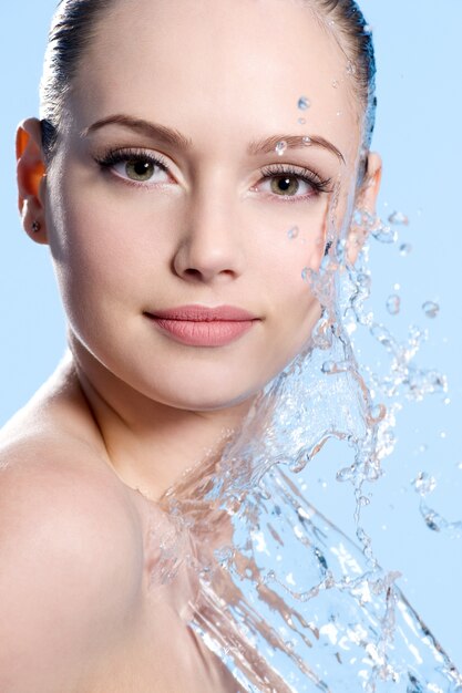 Retrato de rostro femenino joven con salpicaduras de agua - fondo azul