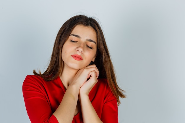 Retrato de señorita almohada cara en sus manos en blusa roja y mirando soñoliento