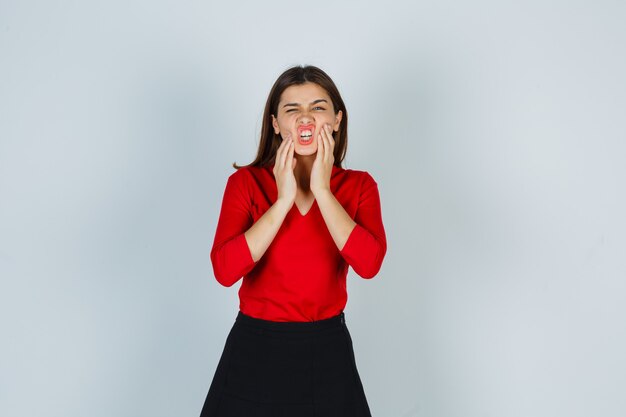 Foto gratuita retrato de señorita cogidos de la mano en las mejillas en blusa roja