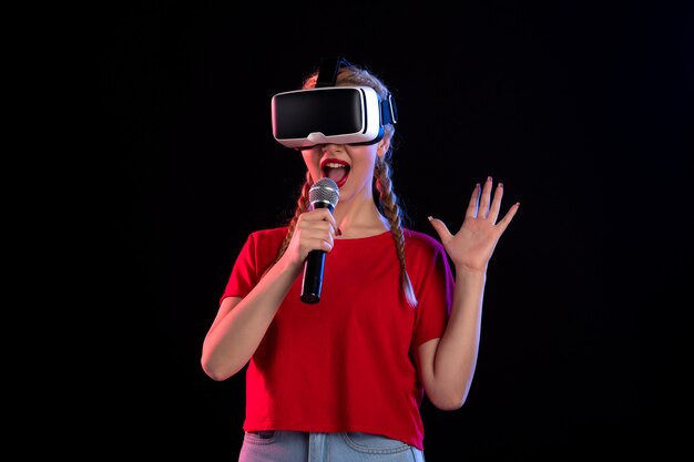 Retrato de señorita jugando vr y cantando en la pared oscura