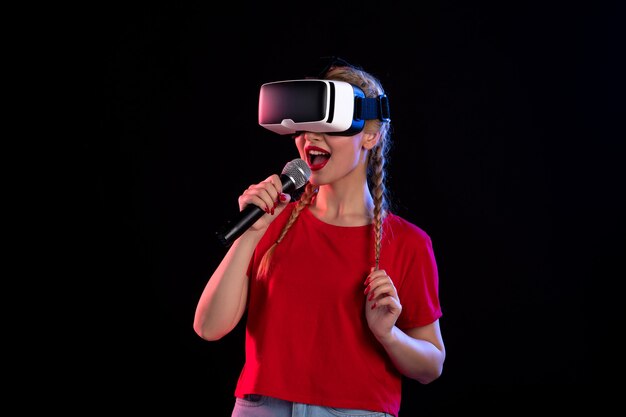 Retrato de señorita jugando vr y cantando en la pared oscura