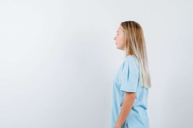 Retrato de señorita mirando a otro lado en camiseta y mirando confiada vista frontal