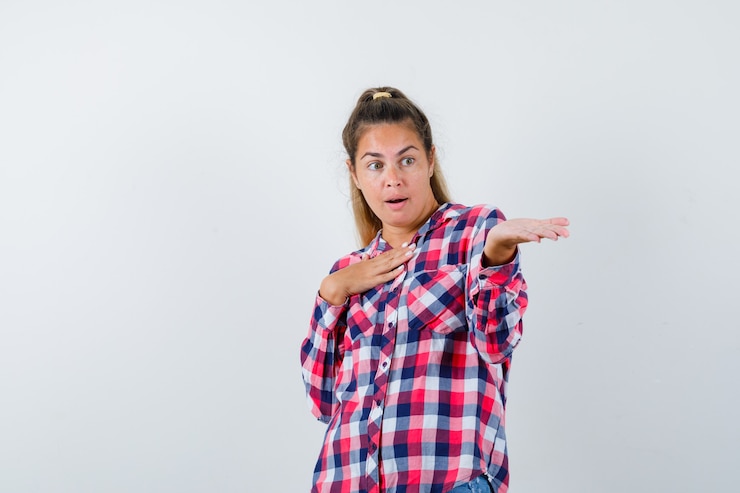 Foto gratuito retrato de señorita mostrando algo en camisa a cuadros y mirando sorprendido vista frontal