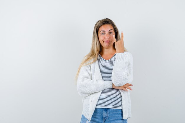 Retrato de señorita mostrando gesto de rock en camiseta, chaqueta y mirando confiado vista frontal