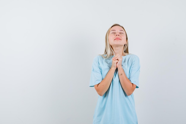 Foto gratuita retrato de señorita mostrando las manos juntas en gesto de súplica en camiseta aislado