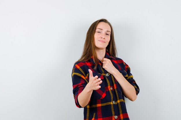 Retrato de señorita ofreciendo la mano para temblar en camisa casual y mirando orgullosa vista frontal