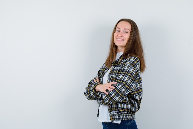 Retrato de señorita de pie con los brazos cruzados en camiseta, chaqueta y mirando confiada vista frontal