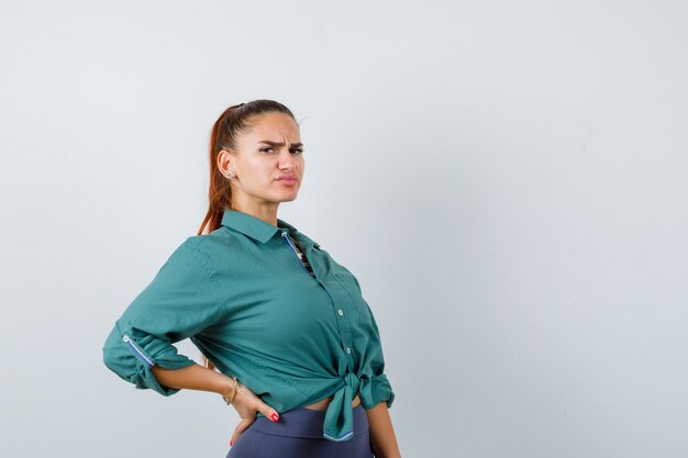 Foto gratuita retrato de señorita que sufre de dolor de espalda en camisa verde y mirando incómodo vista frontal