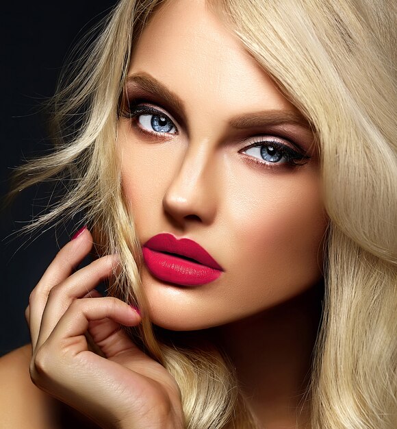 Retrato sensual glamour de hermosa mujer rubia modelo dama con maquillaje brillante y labios rosados, con cabello rizado saludable sobre fondo negro