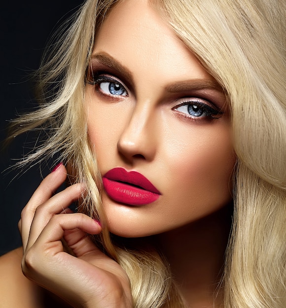 Retrato sensual glamour de hermosa mujer rubia modelo dama con maquillaje brillante y labios rosados, con cabello rizado saludable sobre fondo negro