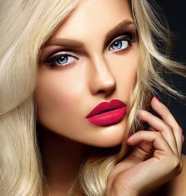 Retrato sensual glamour de hermosa mujer rubia modelo dama con maquillaje brillante y labios rosados, con cabello rizado saludable sobre fondo negro