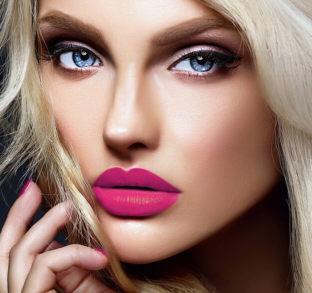 Retrato sensual glamour de hermosa mujer rubia modelo dama con maquillaje brillante y labios rosados, con cabello rizado saludable sobre fondo negro