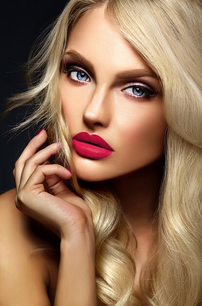 Retrato sensual glamour de hermosa mujer rubia modelo dama con maquillaje brillante y labios rosados, con cabello rizado saludable sobre fondo negro