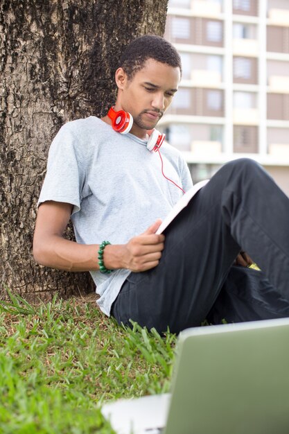 Retrato, serio, macho, estudiante, lectura, al aire libre