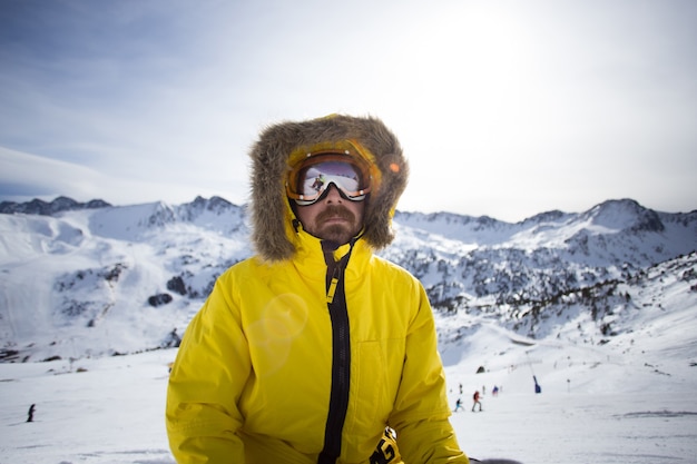 Retrato de snowboarder o esquiador fresco y áspero, o montañero en chaqueta amarilla de invierno cálido