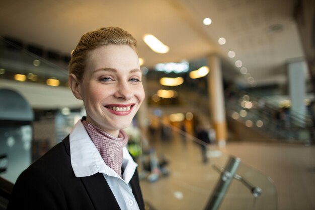 Retrato de sonriente asistente de facturación de la aerolínea en el mostrador