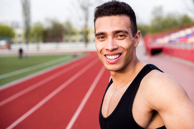 Retrato sonriente de un atleta masculino en la pista de carreras en el estadio