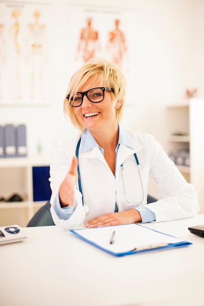 Retrato de sonriente doctora ofreciendo un apretón de manos