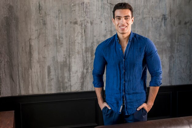 Retrato sonriente de un hombre joven con sus manos en el bolsillo