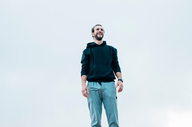 Retrato sonriente de un hombre de pie contra el cielo azul