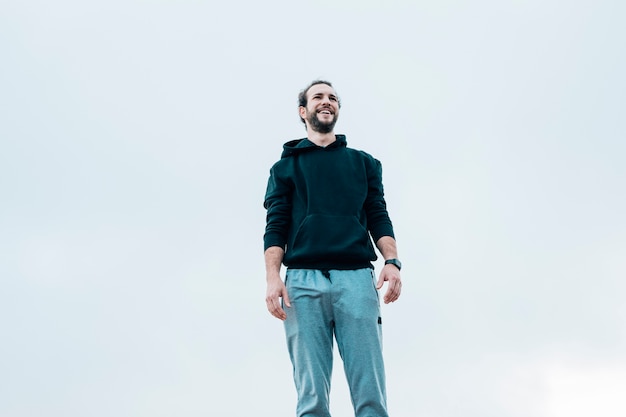 Retrato sonriente de un hombre de pie contra el cielo azul