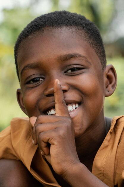 Retrato sonriente joven africano haciendo señal de silencio
