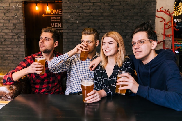 Retrato de un sonriente joven amigos disfrutando de la cerveza
