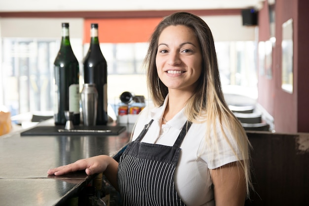 Foto gratuita retrato de sonriente joven camarera en el bar