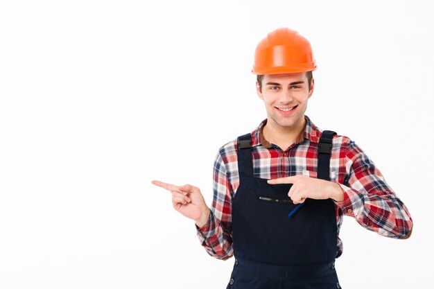 Retrato de un sonriente joven constructor masculino señalando