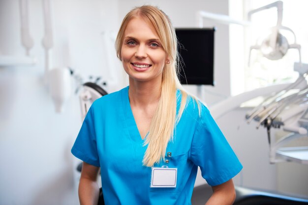 Retrato de sonriente, joven dentista en la clínica del dentista