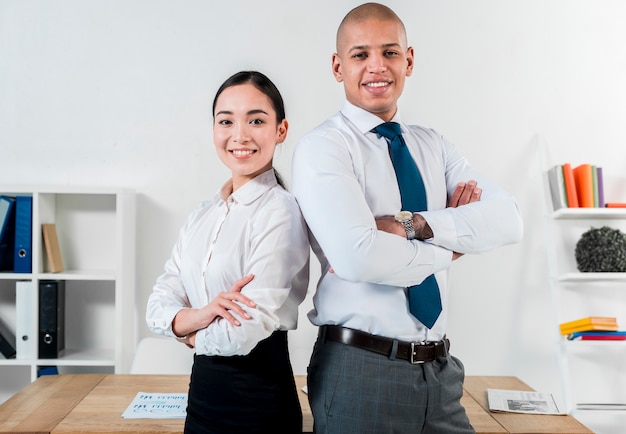 Retrato sonriente de un joven empresario y empresaria de pie de espaldas en la oficina