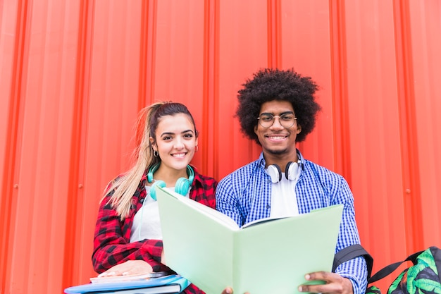 Retrato sonriente de un joven estudiante masculino y femenino estudiando juntos