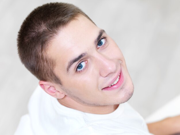 Retrato de sonriente joven hermoso en casa - ángulo alto