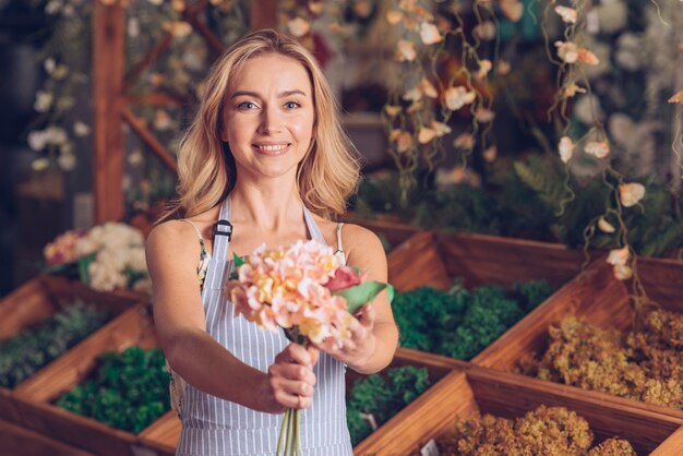 Retrato de sonriente joven mujer florista ofreciendo las flores