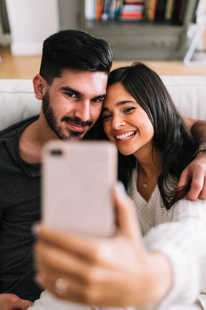 Retrato de sonriente joven pareja tomando selfie en teléfono móvil