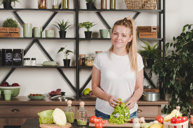 Retrato de sonriente joven rubia preparando la comida