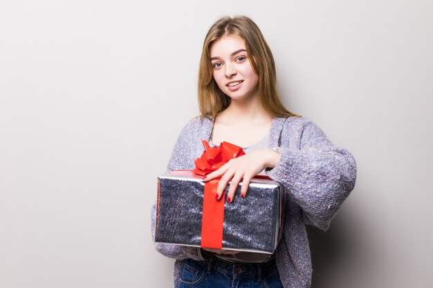 Retrato de una sonriente jovencita linda abriendo caja de regalo aislada