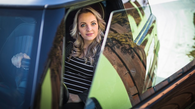 Foto gratuita retrato de una sonriente mujer embarazada sentada en el coche