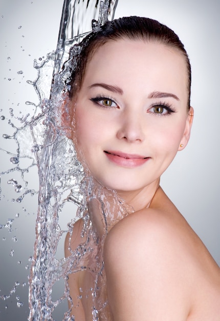 Retrato, de, sonriente, mujer joven, con, agua, en, ella, cara, y, cuerpo