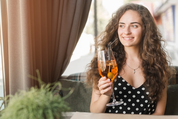 Retrato de sonriente mujer joven y atractiva con vaso de cóctel con oliva