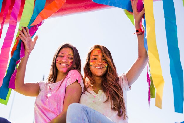 Retrato sonriente de una mujer joven con color holi en su cara mirando a cámara