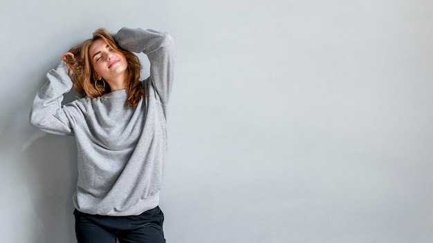 Foto gratuita retrato sonriente de una mujer joven contra la pared gris