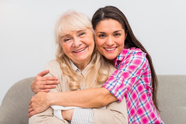 Retrato sonriente de una mujer joven que abraza a su madre mayor