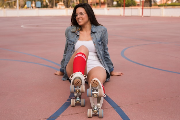 Foto gratuita retrato sonriente de una mujer joven que lleva el patín de ruedas que se relaja en corte