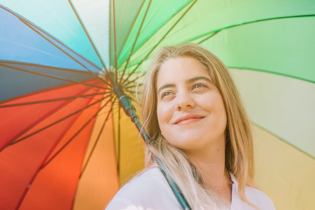 Retrato sonriente de una mujer joven que sostiene el paraguas colorido