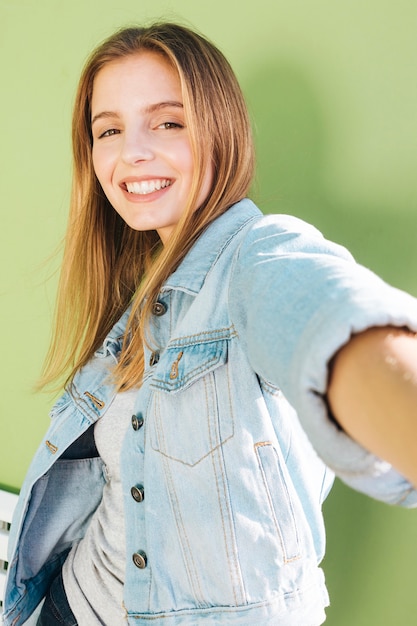 Retrato sonriente de una mujer joven rubia contra el contexto verde