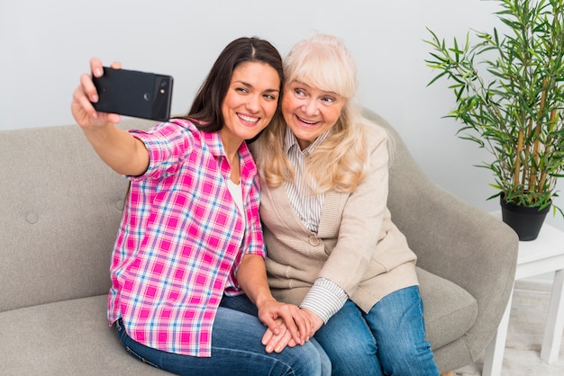 Retrato sonriente de una mujer y una madre mayores que toman el selfie en el teléfono móvil